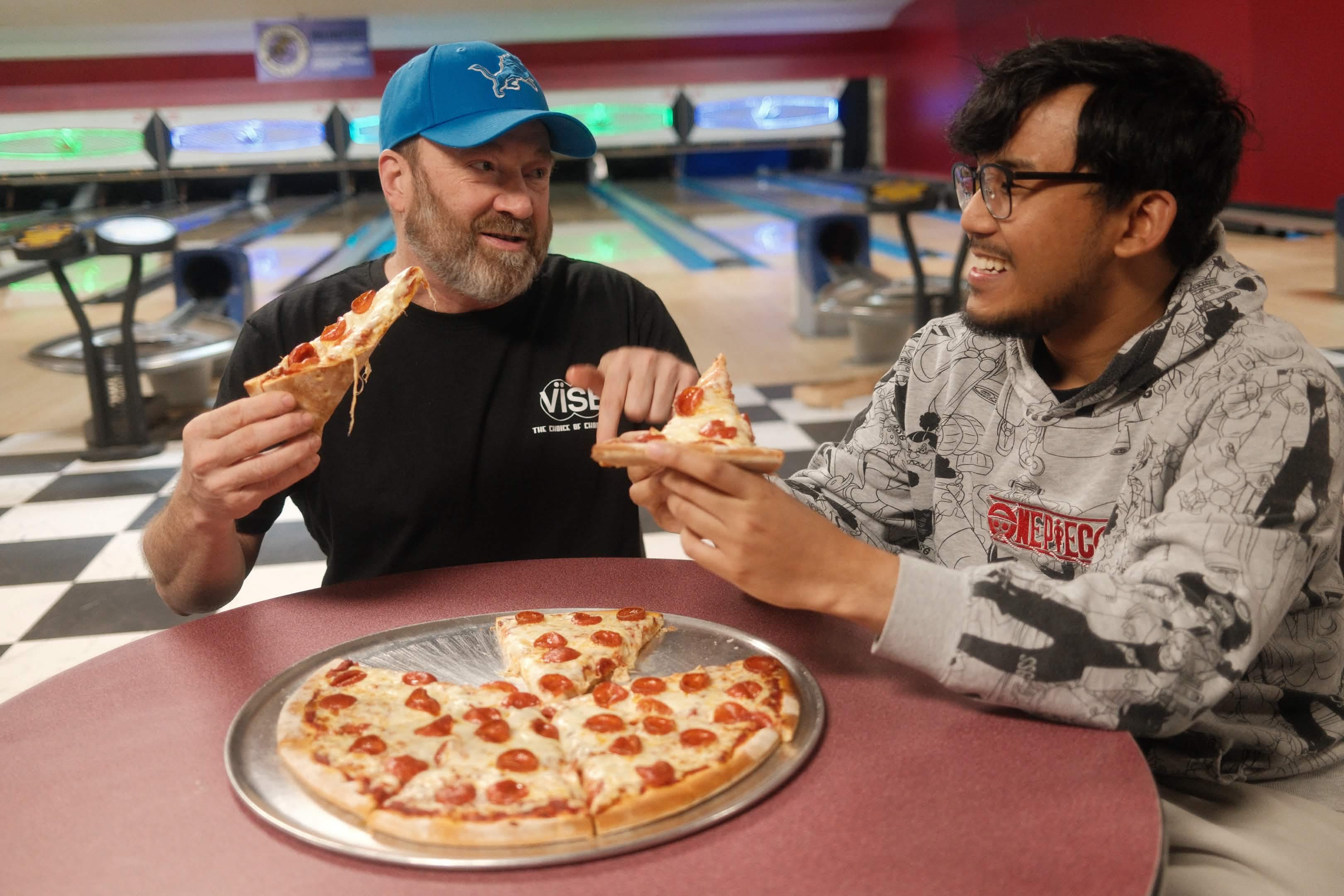 Families eating pizza at the lanes